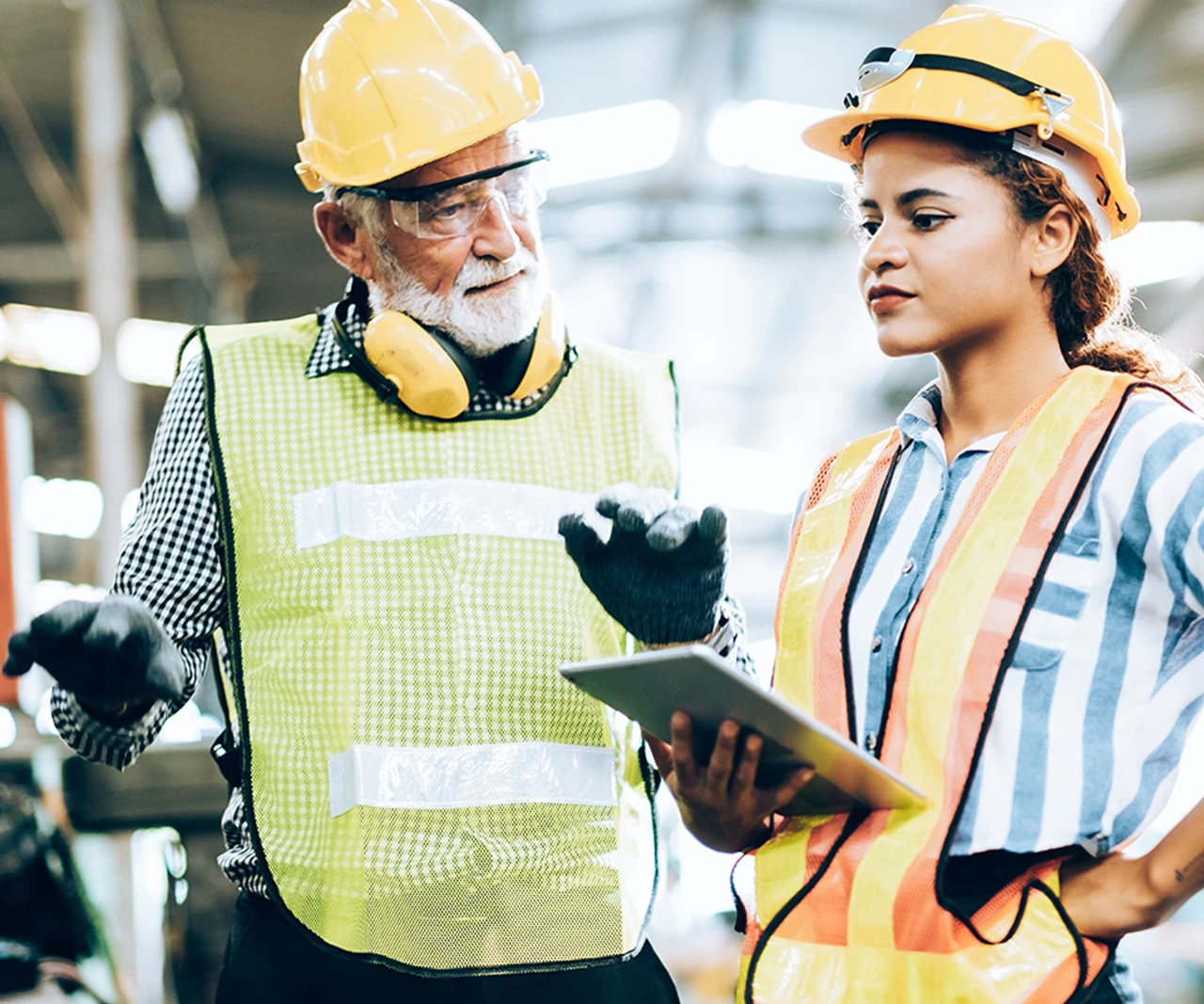 Two workers in hard hats and safety equipment discussing a work order