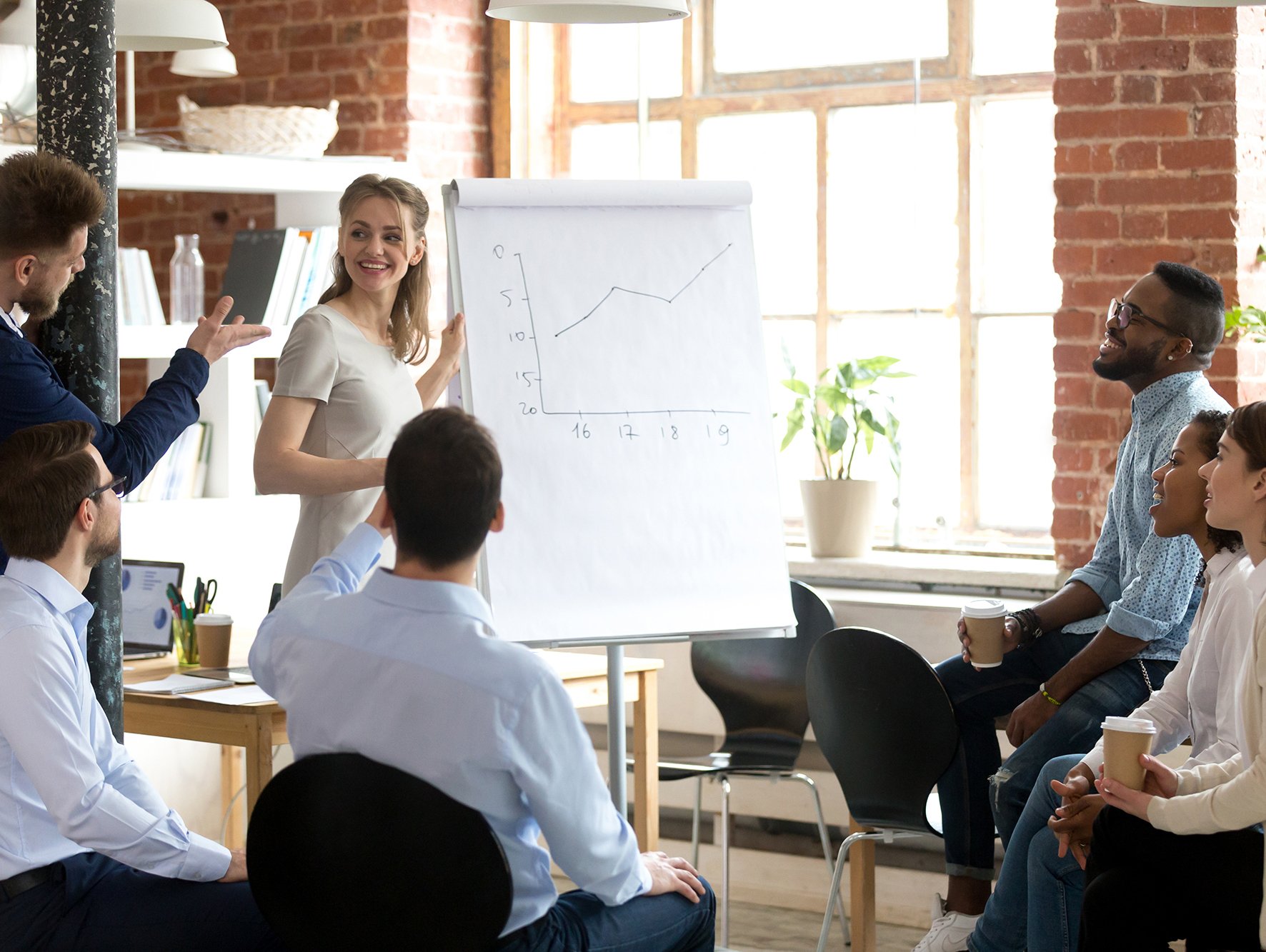 Group of office workers reviewing numbers on flip chart